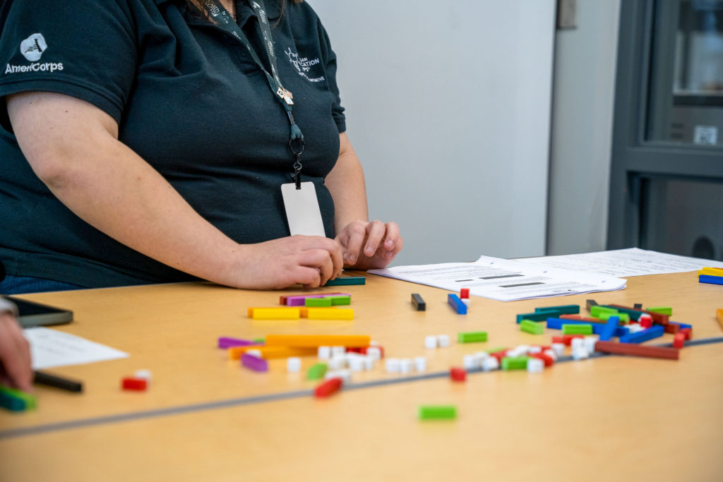 member in black uniform shirt uses math manipulatives to provide intervention